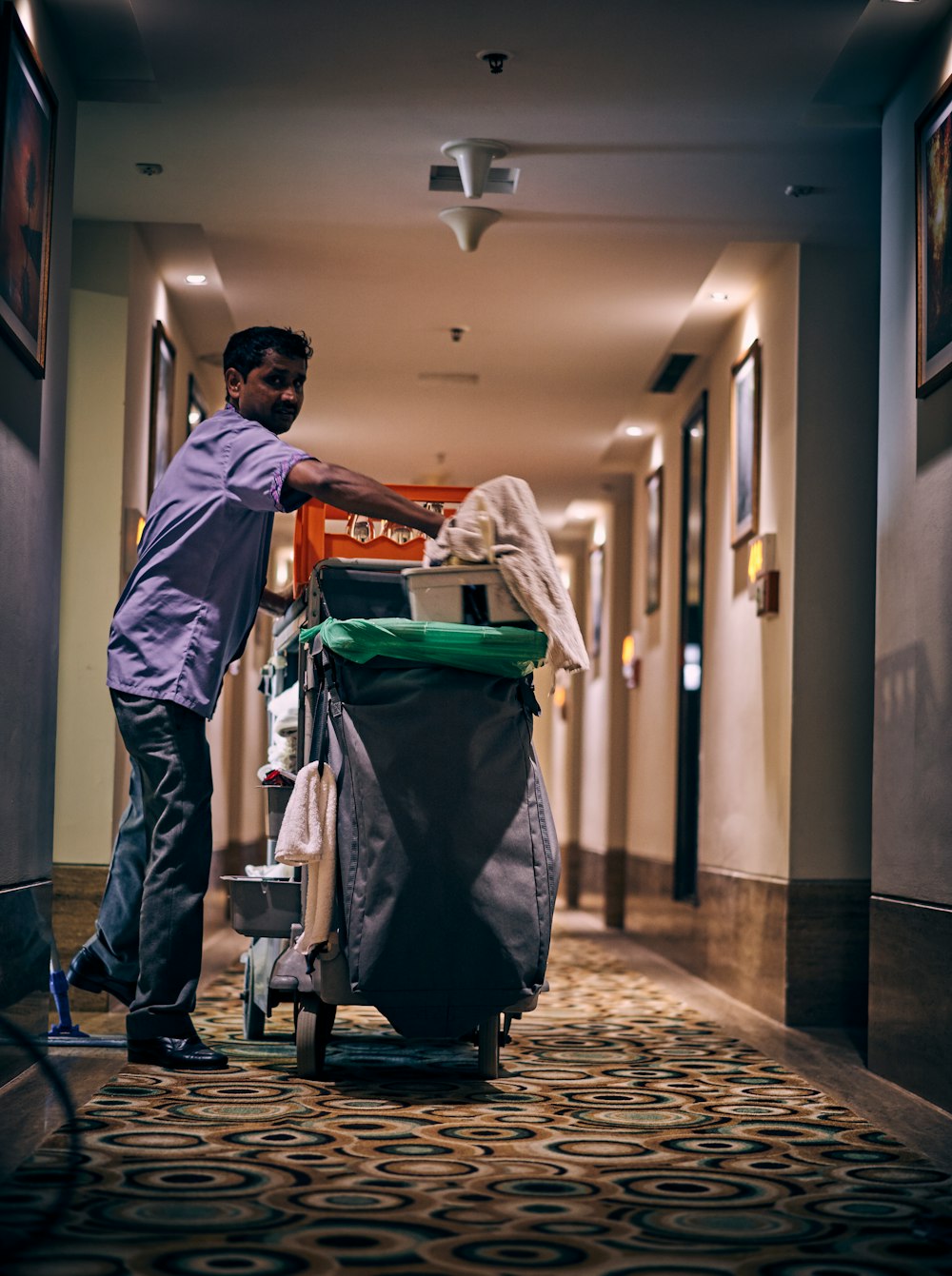 Room cleaning person in a hotel hallway with his equipments